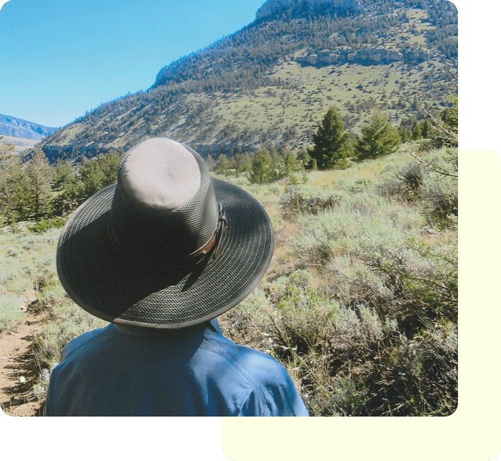 Person wearing a wide-brim hat looking at a mountain landscape.