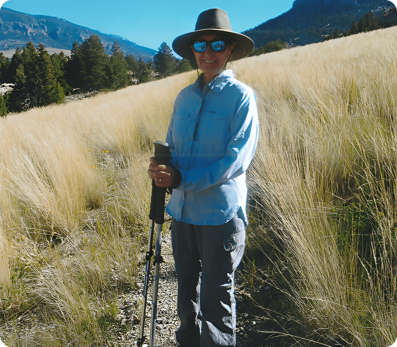 Person hiking on a trail with mountains in the background.